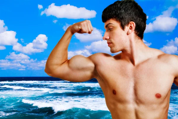 М'язистий чоловік показує свої біцепси на пляжі — стокове фото