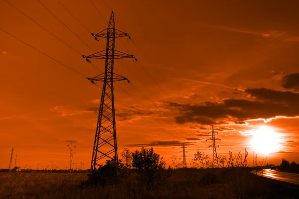 Zon en elektriciteit - elektriciteitsnet torens bij zonsondergang — Stockfoto