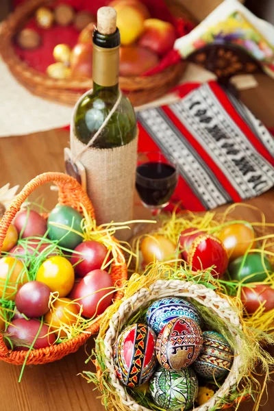 Uova di Pasqua vino e ornamenti sulla tavola — Foto Stock