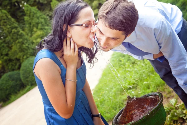 Happy romantic couple drinking water from park fountain — Stock Photo, Image