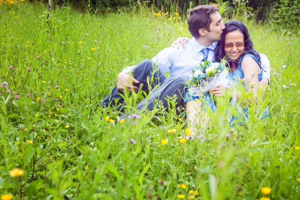 Couple having a candid romantic kiss in the grass — Stock Photo, Image