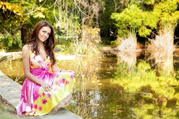 Elegante mooie vrouw met kleurrijke jurk buiten — Stockfoto