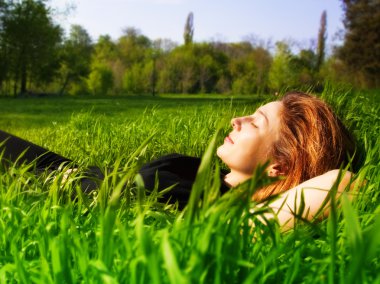 Serene woman relaxing outdoor in fresh grass clipart