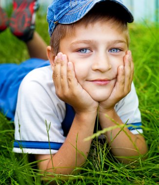 Cute happy kid laying on grass outdoor clipart