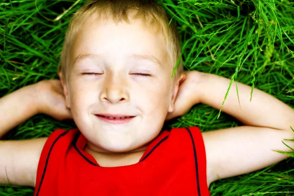 Niño feliz soñando en hierba fresca —  Fotos de Stock