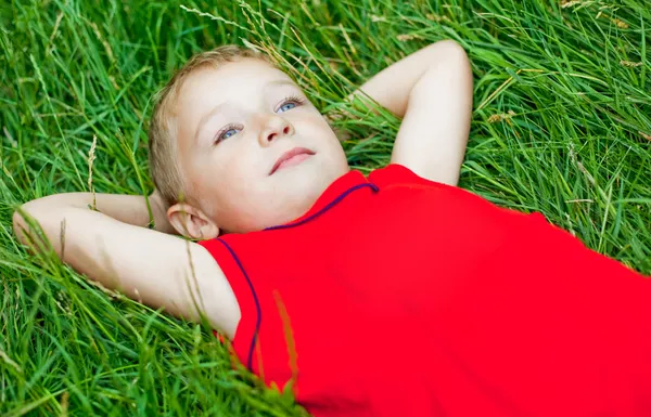 Día de niño pensativo soñando en hierba fresca — Foto de Stock