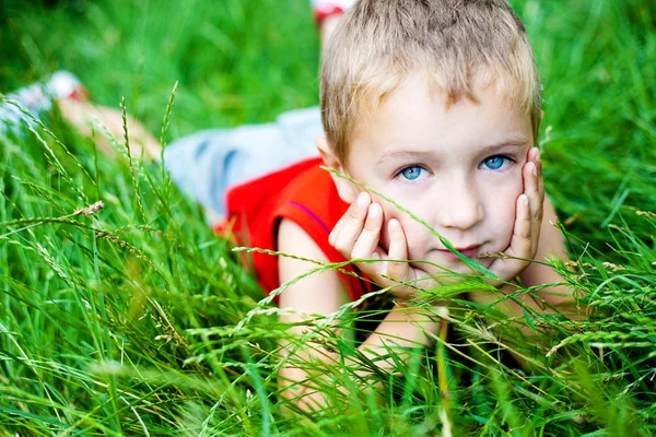 Aranyos fiú pihentető, a zöld friss fű — Stock Fotó