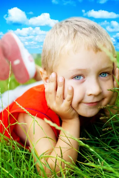 Sorriso de criança bonito feliz na grama da primavera — Fotografia de Stock