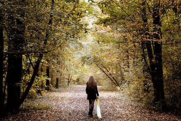 Грустная женщина, гуляющая одна в лесу

