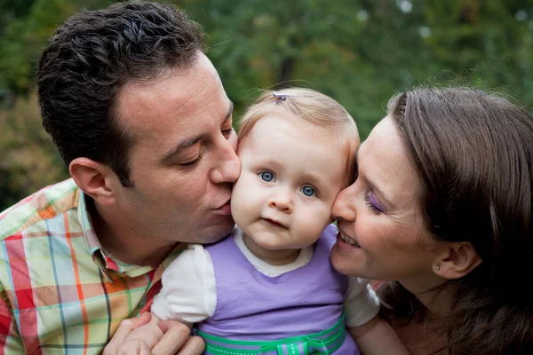 Familie liefde - ouders kus voor dochter — Stockfoto