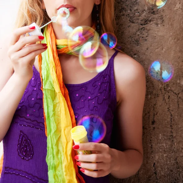 Woman blowing colorful soap bubbles — Stock Photo, Image