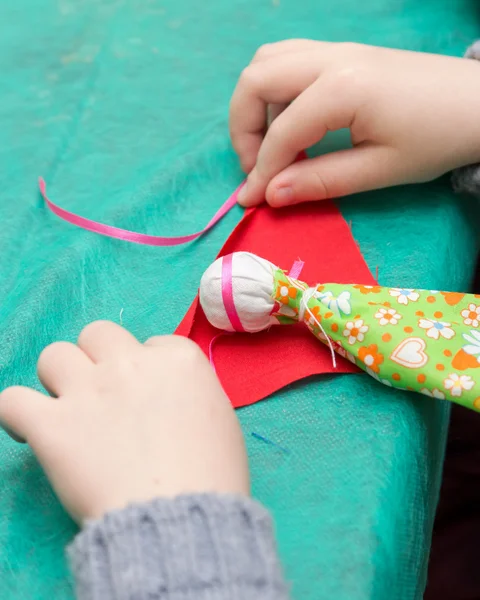 Ребенок делает традиционную игрушку из разных тряпок — стоковое фото