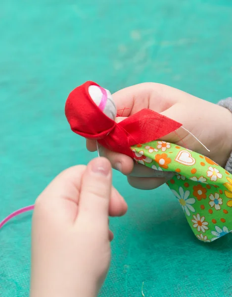 The child makes a traditional toy from different rags — Stock Photo, Image