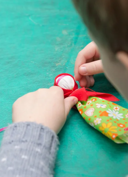 The child makes a traditional toy from different rags — Stock Photo, Image