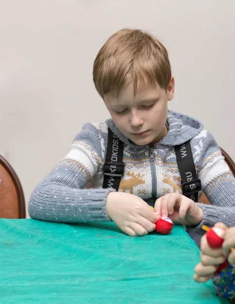 Het kind maakt een traditionele speelgoed uit verschillende lompen — Stockfoto