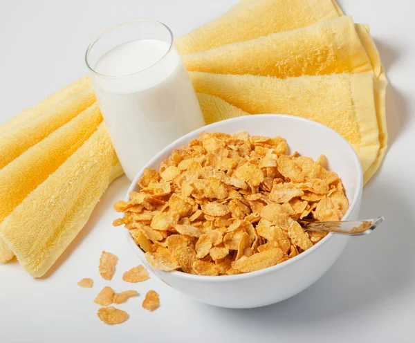 stock image Corn flakes in deep plate with spoon, glass with milk and yellow towel. A breakfast.