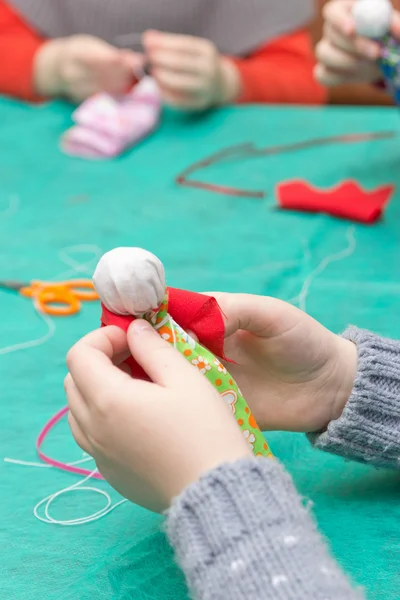 The child makes a traditional toy from different rags — Stock Photo, Image