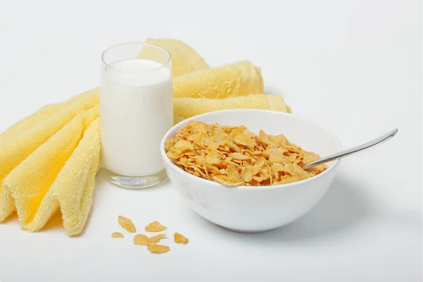 stock image Corn flakes in deep plate with spoon, glass with milk and yellow towel.