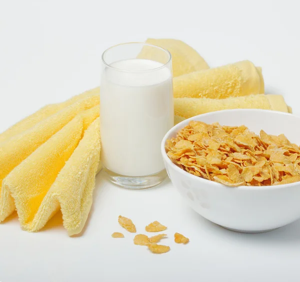 Stock image Corn flakes in deep plate with spoon, glass with milk and yellow towel.