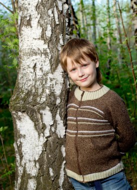 Smiling cute boy in spring forest clipart