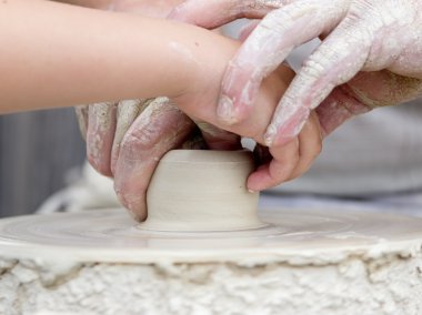 Artisan learning a child to make potter from white clay. clipart