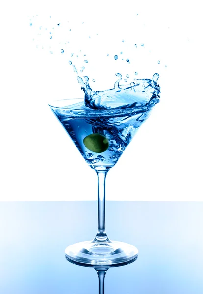 Blauwe martini met olijfolie in glas. Splash met druppels op witte achtergrond. — Stockfoto