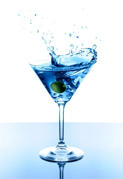 Martini azul con aceituna en vidrio. Salpicadura con gotas sobre fondo blanco . — Foto de Stock