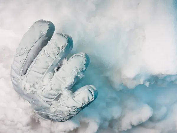 Enterrado vivo. Un guante sobresaliendo de una deriva de nieve con profundas sombras azules . — Foto de Stock