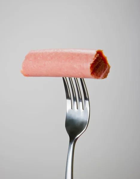 stock image Sausage on the fork over gray background.