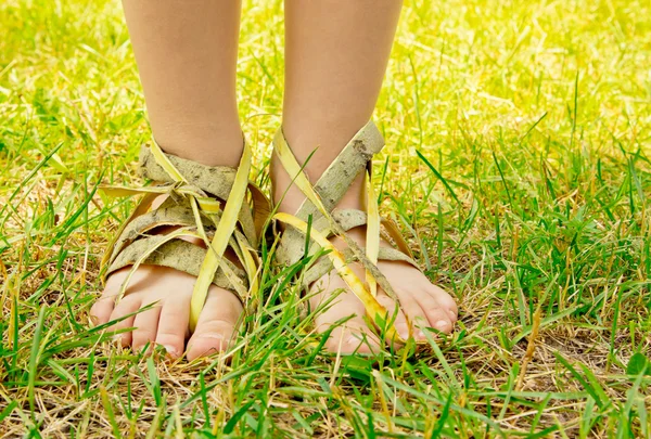 Pies abstractos en el calzado de corteza en la hierba. Concepto de calzado ecológico . — Foto de Stock