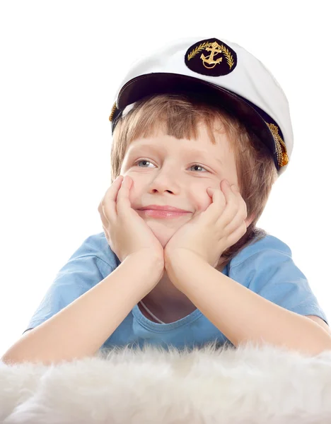 Mignon enfant rêveur en bonnet de capitaine repose sur la fourrure de mouton doux isolé sur fond blanc. Clé haute . — Photo