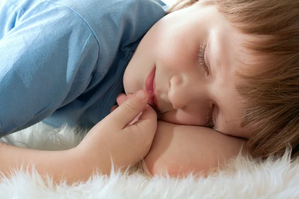 Roztomilý chlapec spí na bílé srsti. Hezky spi. — Stock fotografie
