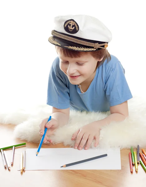 Cute dreaming child in captain cap lies and draw on soft sheep fur isolated — Stock Photo, Image