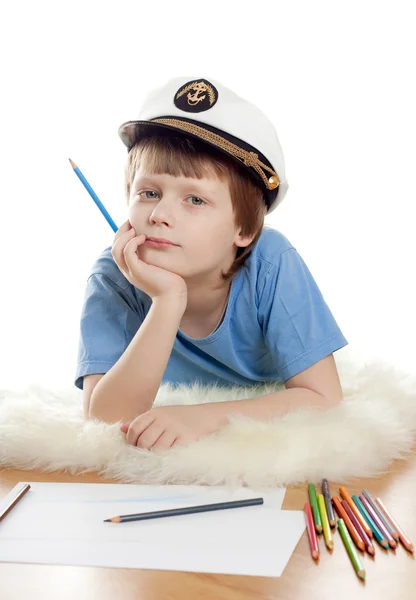 Lindo niño soñador en gorra de capitán se encuentra en piel de oveja suave aislado sobre fondo blanco. Clave alta . — Foto de Stock