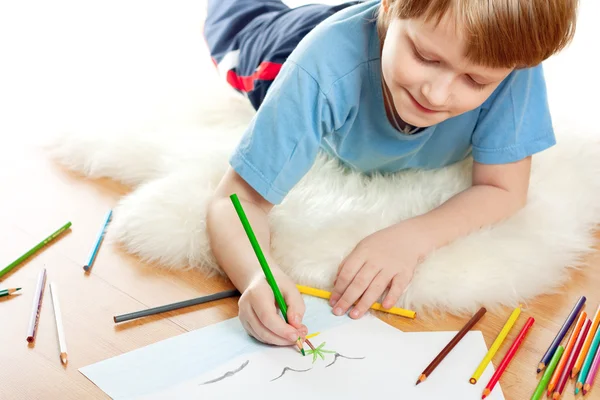 Niedlich träumendes Kind lügt und zeichnet auf weichem Schaffell isoliert über weißem Bac — Stockfoto