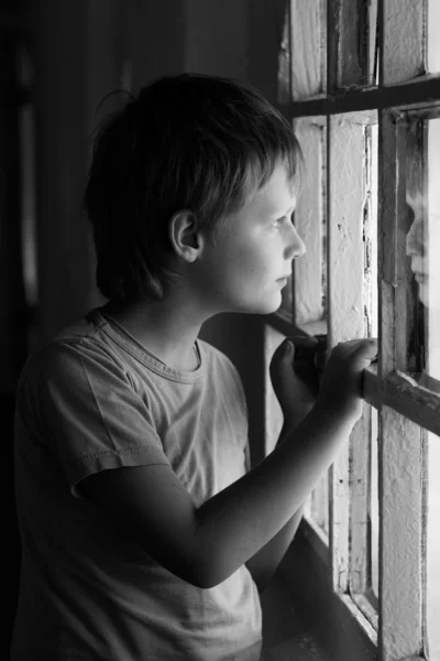 Rapaz triste a olhar pela janela. Preto e branco . — Fotografia de Stock