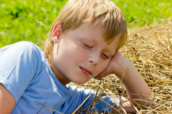 Chlapec si odpočinout na kupce sena. — Stock fotografie