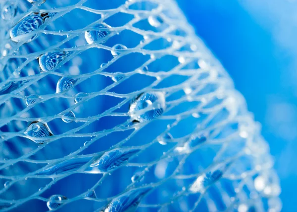 Foto macro abstrata da esponja de banho azul de massagem com gotas de água . — Fotografia de Stock