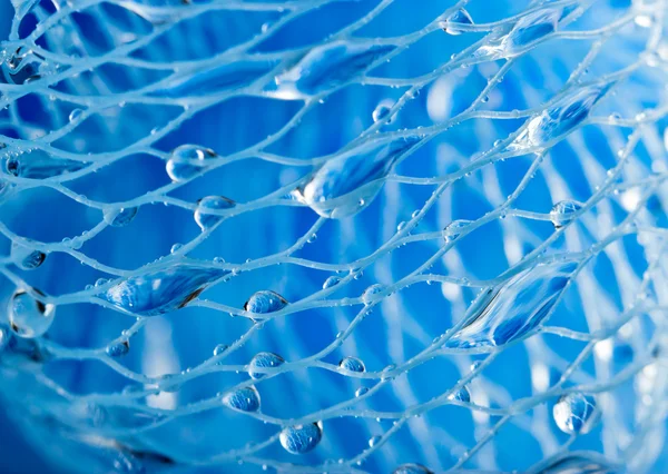 Foto macro abstrata da esponja de banho azul de massagem com gotas de água . — Fotografia de Stock