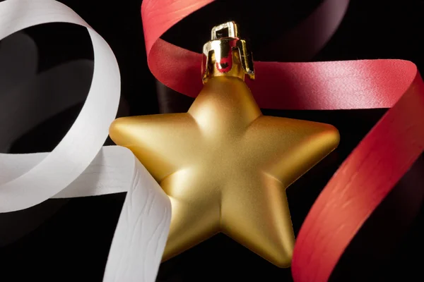 Goldener Stern auf schwarzem Hintergrund mit weißen und roten Bändern. — Stockfoto