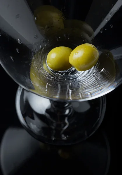 Două măsline verzi așteaptă când alcoolul va umple paharul. Ajută-i . — Fotografie, imagine de stoc