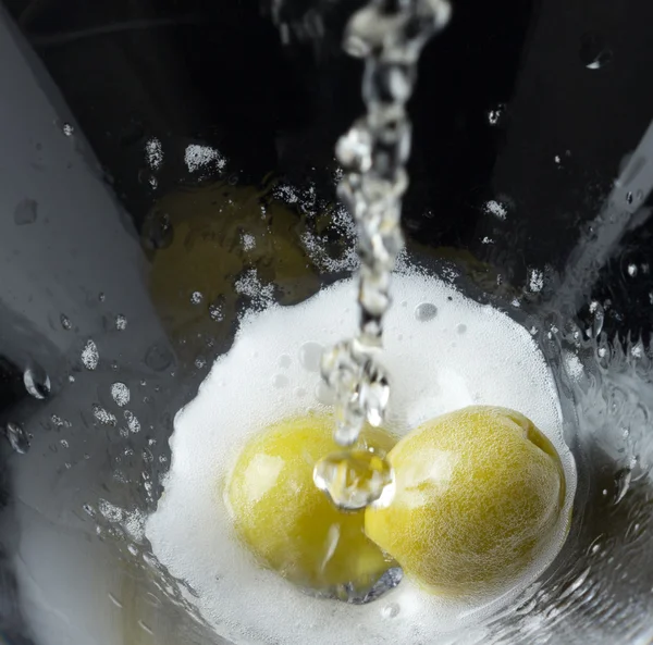 Two green olives in a fresh flow of champagne wine. — Stock Photo, Image