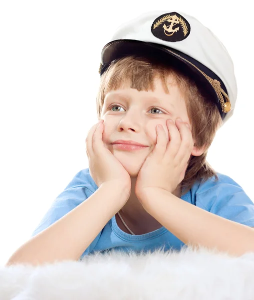 Niedliche träumende Kind in Kapitänsmütze liegt auf weichem Schaffell isoliert über whi Stockfoto