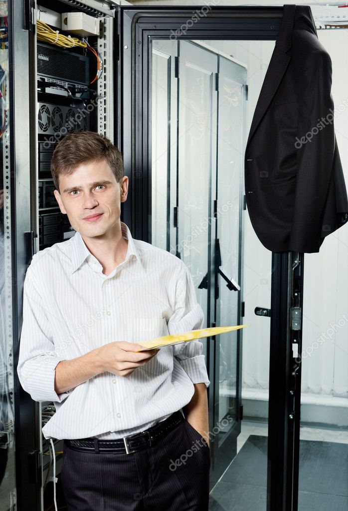 The engineer in suit stand in datacenter near telecomunication equipment ho