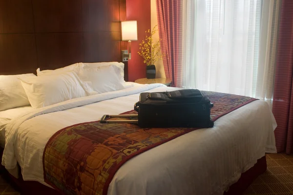 Suitcase on hotel bed — Stock Photo, Image