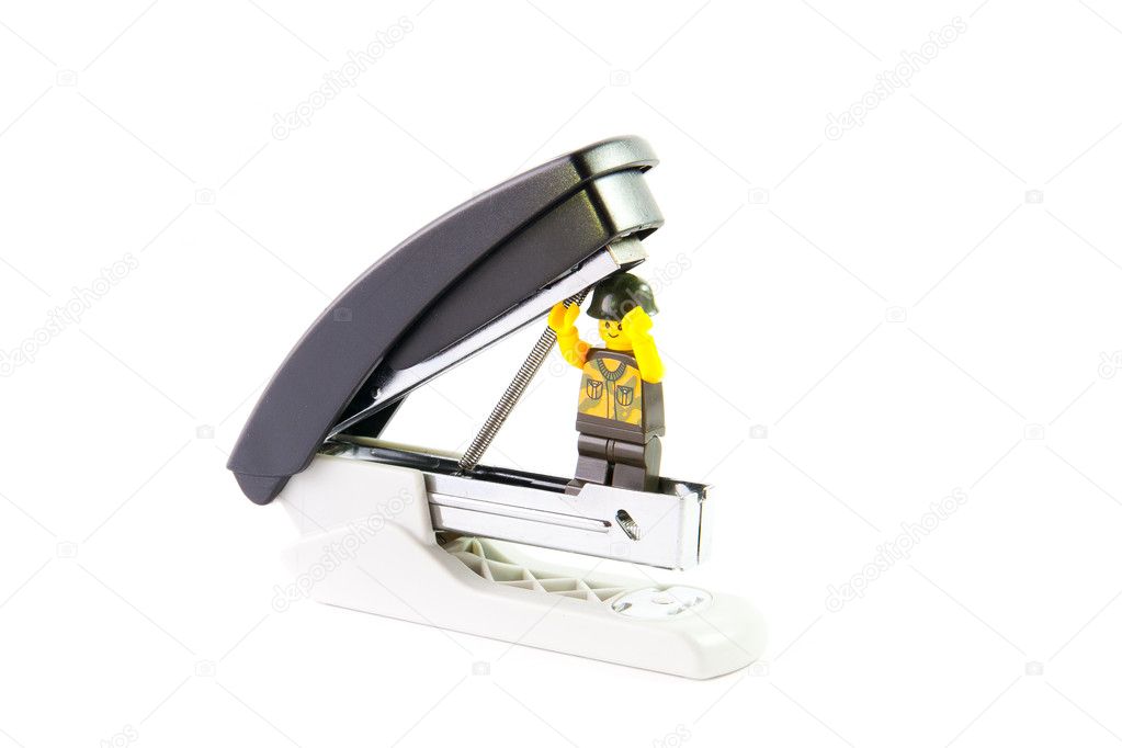 Toy plastic man holding open a stapler