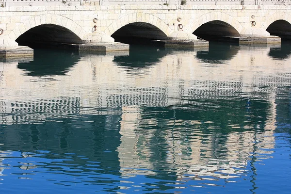 Steen arch bridge en weerspiegeling in geschiedenis water — Stockfoto