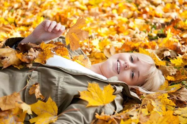 Junge Frau liegt im Herbstlaub — Stockfoto