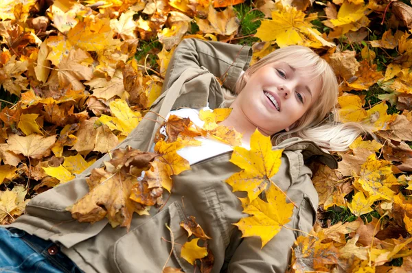 Mujer joven acostada en hojas de otoño — Foto de Stock