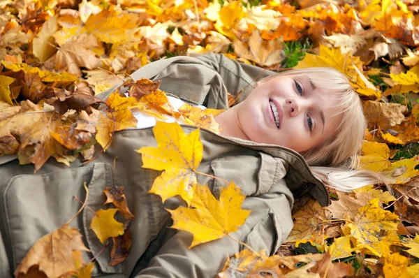 Молодая женщина лежит в осенних листьях — стоковое фото